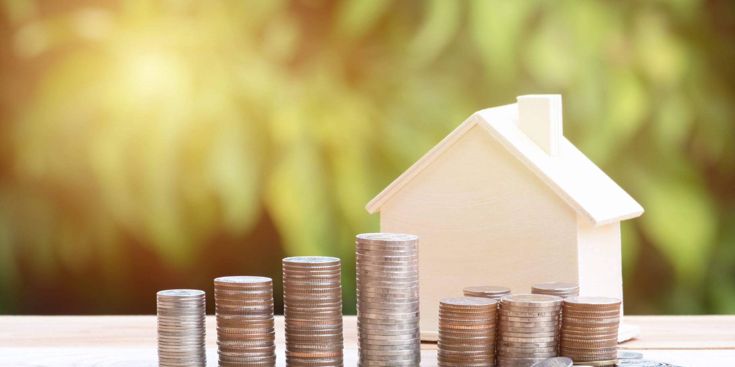 View Of coin stack with house model on green background, savings