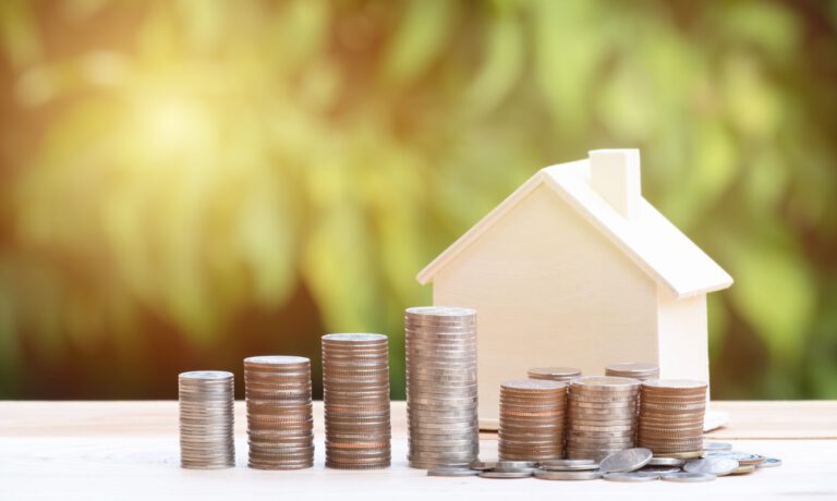 View Of coin stack with house model on green background, savings