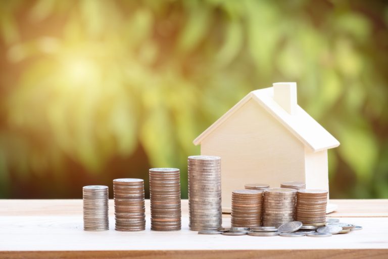 View Of coin stack with house model on green background, savings